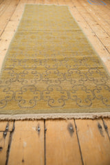 Close-up of gold and saffron Khotan runner's reciprocating floral panel design, with time-softened pile.