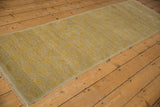 Golden yellow distressed Khotan runner, visible floral panel motif, soft abrashes, and secure selvage.