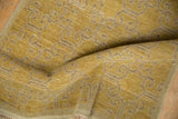 Distressed gold Khotan rug's repeating floral panel motif with abrashes and visible foundation.
