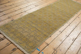 Distressed Khotan runner end with intact fringe, showing worn pile and floral panel motif.