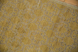 Textured, distressed golden-yellow Khotan rug with visible curvilinear motif and surface wear.