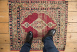 Antique Kerman rug's cochineal field, diamond medallion, and millefleur, showing wear and exposed foundation.