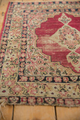 Antique Kerman rug with a worn cochineal red field and intricate ivory millefleur border.