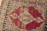 Detail of antique Kerman rug's cochineal red field with millefleur motifs and visible foundation wear.