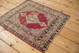 Close-up of antique Kerman rug's cochineal red field with navy millefleur border, showing foundation wear.