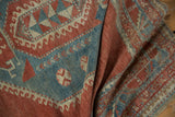 Distressed texture and geometric patterns in pale cinnabar red, powder blue, and ivory.