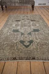 Distressed vintage Persian Hamadan rug's shield medallion, finials, and boteh in muted silver, pale blue, beige.