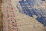 Detail of vintage distressed Oushak carpet's faded blush border and worn royal denim blue on abrashed ground.