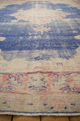 Distressed vintage Oushak carpet pile: dark blue, faded red, exposed foundation.