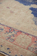 Distressed vintage Oushak carpet pile with faded blush red, denim blue, and beige.