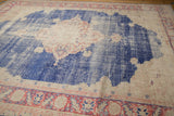 Textured view of distressed Oushak rug, showing faded blue, beige, and blush red tones.