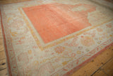 Vintage Oushak carpet's abrashed pale tangerine field and wide ivory border with saffron patterns.