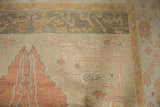 Vintage Oushak carpet's pale tangerine prayer motif on abrashed ivory field, oxidized silver border.