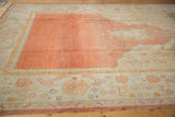Vintage Oushak rug corner with pale tangerine abrashed field and wide ivory border.