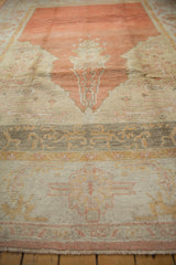 Geometric patterns in oxidized silver, saffron, and tangerine on the wide Oushak border.