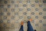 Distressed Sivas carpet field with dusty navy trellis design, germinating plants, and Herati border.