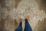 Distressed vintage Oushak rug in abrashed beige, sand, and coffee brown tones, featuring geometric motifs.