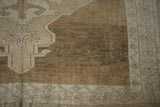 Close-up of a vintage distressed Oushak rug, showing abrashed coffee brown field and stylized beige patterns.
