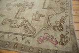 Distressed Oushak rug corner with faded beige scrolling floral patterns, pink motif, and geometric border.