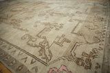 Distressed Oushak rug with geometric border, soft beige pile, and subtle pale pink accents.