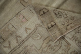Folded vintage distressed Oushak rug showing ivory foundation and textured pile with visible knot heads.