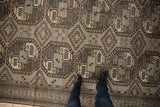 Distressed Ersari carpet displaying repeating geometric guls and softened silver, charcoal, and ivory tones.