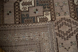 Intricate geometric border patterns and time-softened pile on a distressed Ersari rug.