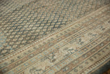 Distressed vintage Mir Sarouk rug showing muted field texture and geometric border details.