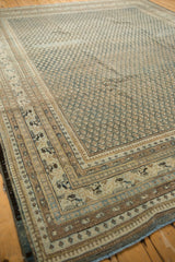 Distressed Persian Mir Sarouk carpet corner, showing muted blue field and intricate borders.
