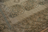 Distressed Ersari carpet close-up: geometric border with dusty blue, ivory, and brown motifs.
