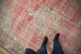 Distressed Oushak carpet, a blend of faded red, beige, and oxidized silver with textural wear.