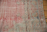 Distressed Oushak rug showing worn red pile texture and exposed foundation.