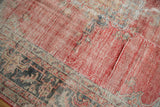 Distressed vintage Oushak carpet showing worn pile texture and pale red field.
