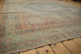 Artfully worn pile of antique Kerman carpet, featuring faded millefleur design in dusty teal and pale red.