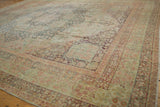 Distressed antique Kerman rug corner with scalloped spandrel, dusty teal, and red millefleur.