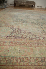 Distressed Kerman carpet's faded dusty teal, pale red, and ivory millefleur pattern.