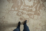 Distressed vintage Oushak rug with muted beige and coffee brown scrolling pattern, showing even wear.