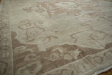 Distressed vintage Oushak rug's textured pile and meandering vine patterns in ivory and beige.