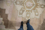 Distressed Vintage Oushak carpet with faded pale pink, beige, and brown geometric patterns.