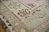 Geometric patterns, visible knot heads, and pale pink highlights on distressed Oushak rug.