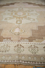 Distressed vintage Oushak rug section with roundel motif, abrashes, and subtle beige-pink hues.