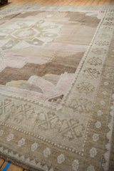 Vintage distressed Oushak rug corner, geometric border, soft beige and pink pile abrashes.