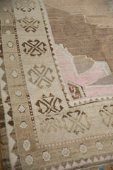 Beige distressed Oushak rug border detail with geometric brown patterns and pale pink spandrel.