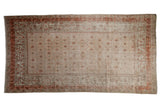 Distressed vintage Khotan carpet with worn beige field and terracotta floral lattice.