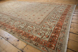 Distressed Khotan carpet with worn field and stylized floral border in terracotta tones.