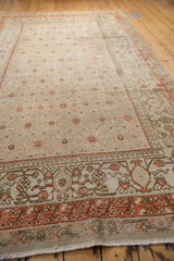 Distressed vintage Khotan rug close-up: worn dusty terracotta border with floral details.