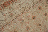 Folded vintage Khotan carpet with distressed floral lattice in terracotta, beige, and brown.