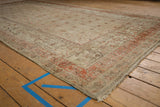 Corner of vintage distressed Khotan carpet with faded terracotta borders and textured wear.