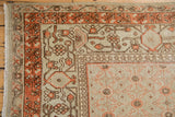 Distressed vintage Khotan carpet corner, displaying burnt orange and chocolate brown floral lattice border.