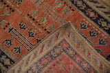 Folded vintage Khotan runner shows tomato red pile, geometric patterns, and detailed woven back.